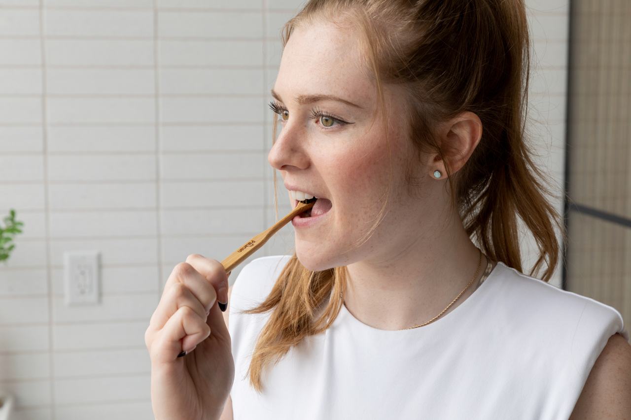 Woman using a bamboo toothbrush